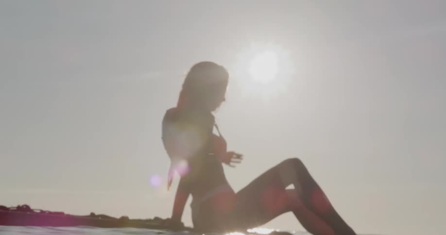 Silhouette of a woman wearing a swimsuit under a bright sun in a clear sky