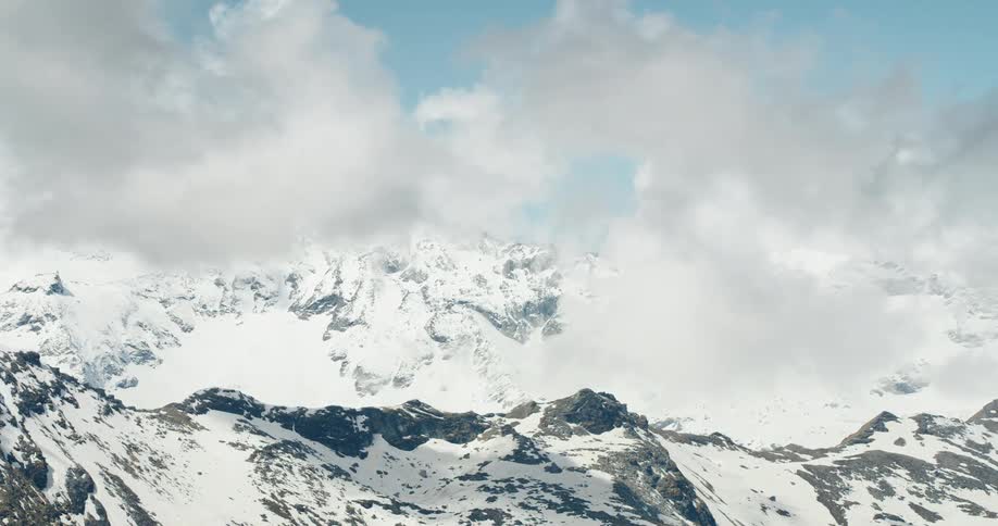 Snowy mountain ranges with clouds nearby