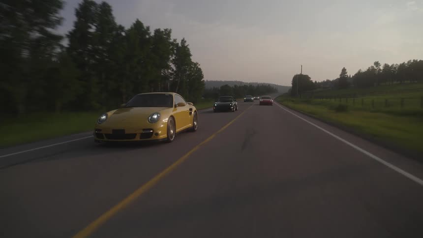 A line of sports cars drive down the road