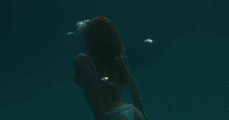 A woman slowly swims underwater to the surface