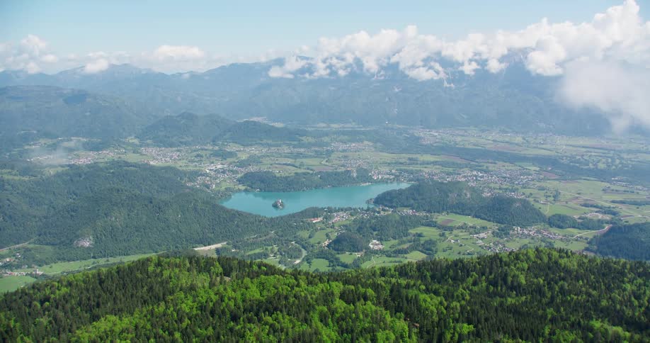 Forest covered plateau towers over a town surrounding a lake in a foggy valley
