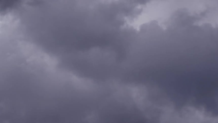 Several gray clouds in the sky moving quickly