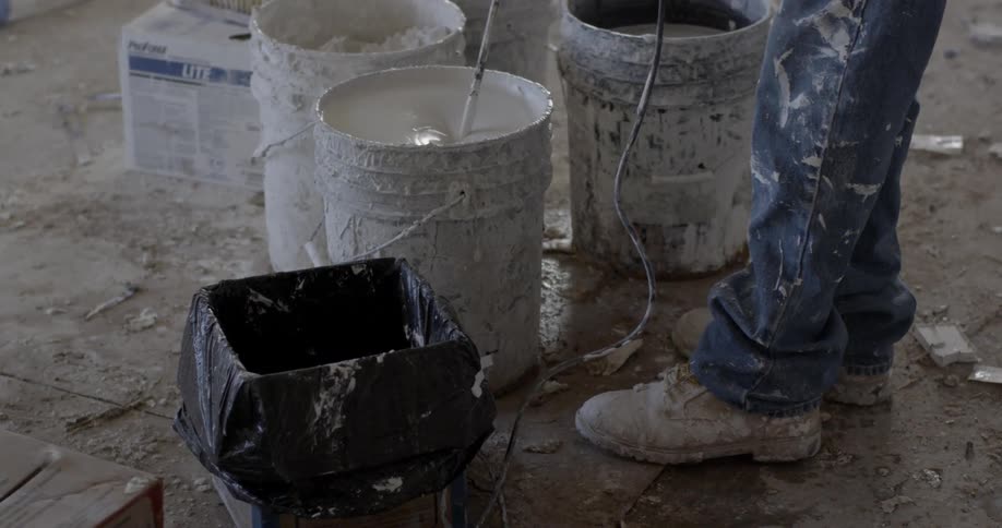 A man is mixing paint in a bucket