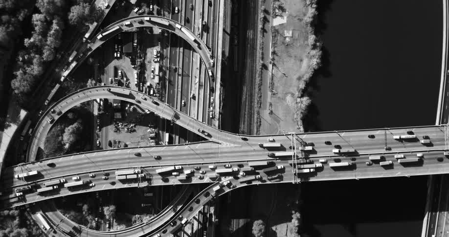 Aerial view of overpasses and highways with vehicle traffic and at the edge of a river