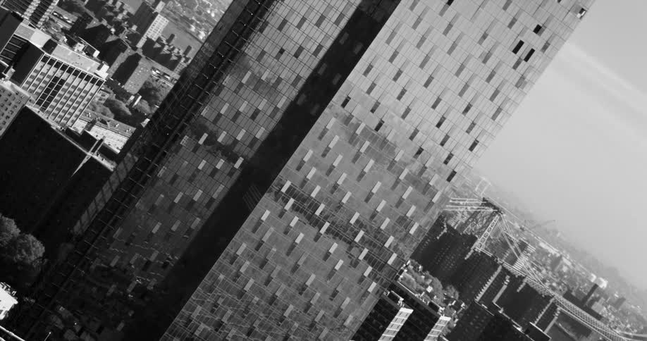 An aerial view of a commercial building with its glassfilled exterior in black and white tones