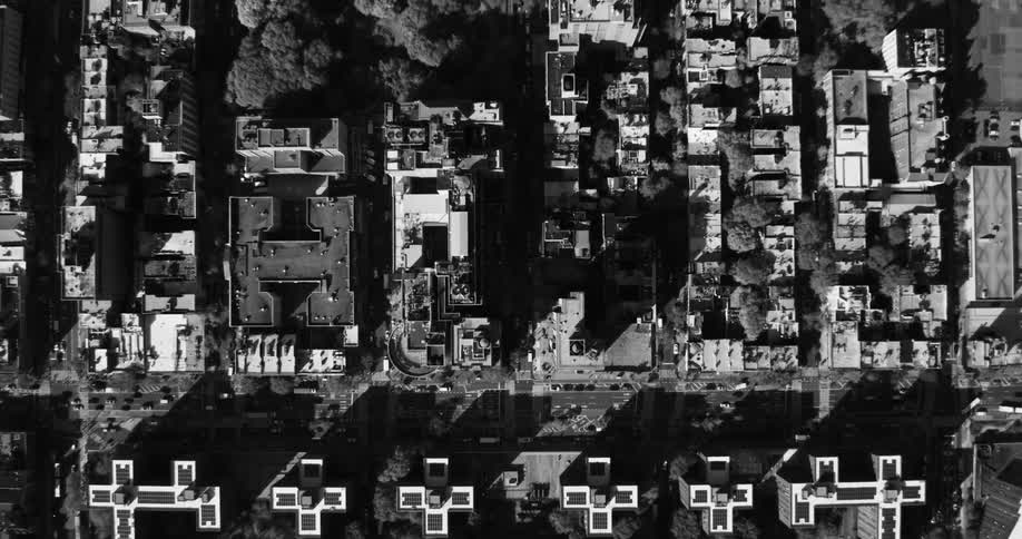 An aerial black and white footage of a symmetrical geometric pattern of buildings in the city
