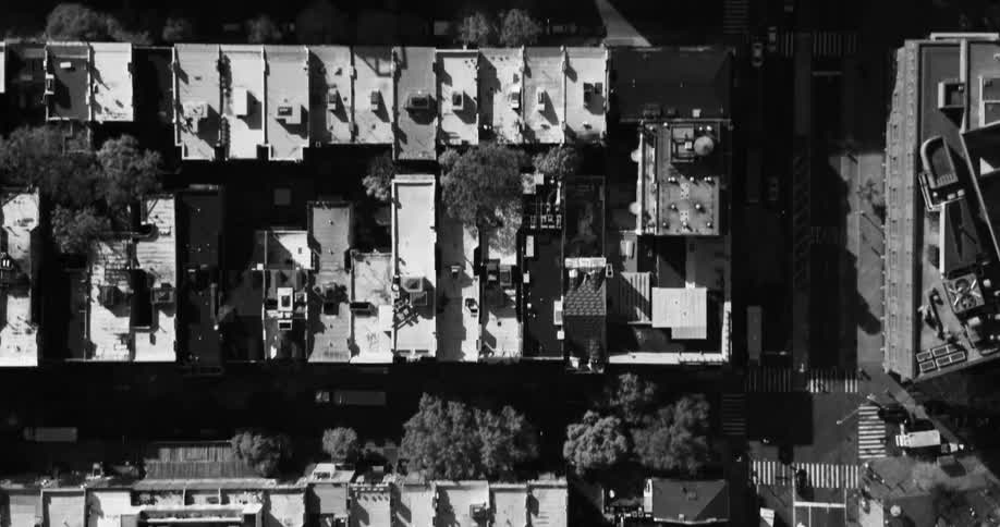 Traffic moves along streets and through intersections between buildings