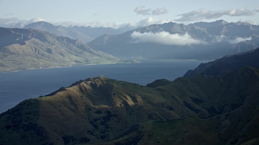 Clouds float above mountains surrounding a large lake