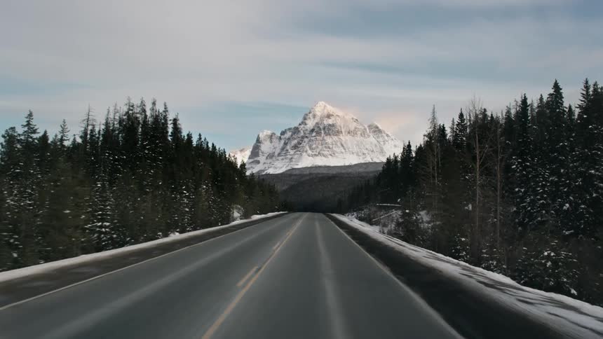 A road heads in the direction of a snow covered mountain