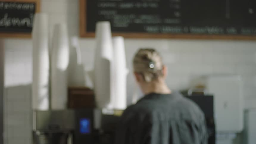 Woman working front counter in coffee shop handles order for customer