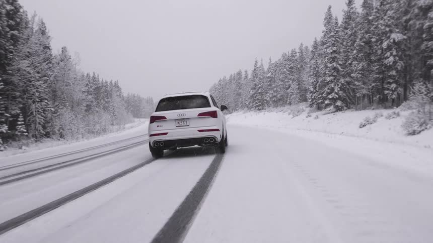White suv drives snow covered road in winter