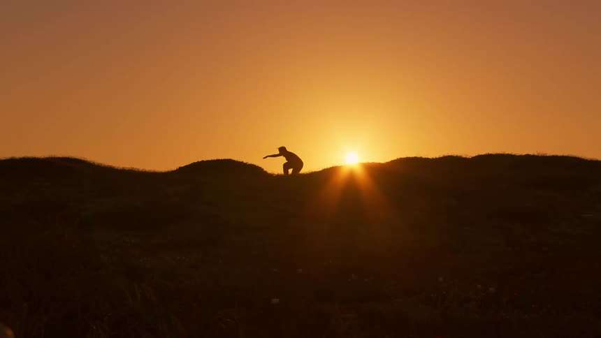 A woman dancing on a hills ridge at sunrise