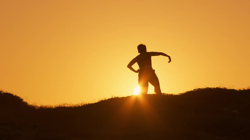 The sun rises as a woman does tai chi