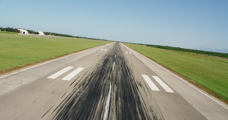 An airplane landing strip with black lines of burnt rubber on the surface