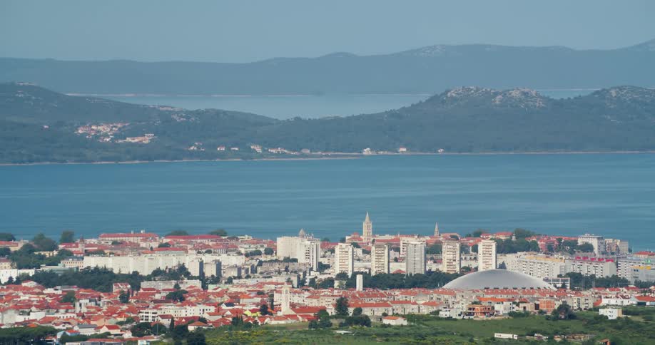 Large town occupies land across the water from foggy mountains