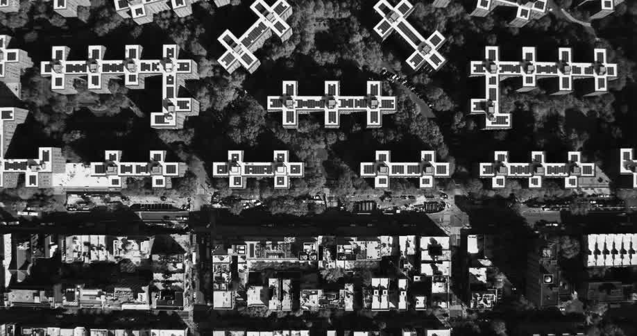 An aerial view of a metropolitan area of several condominiums in a park full of trees in black and white tones
