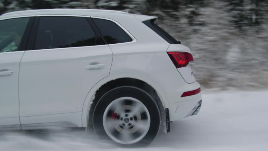 A white car drives in the snow