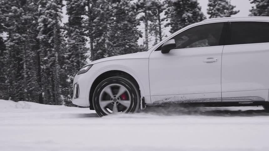Side view of a white car traveling down a snowcovered road