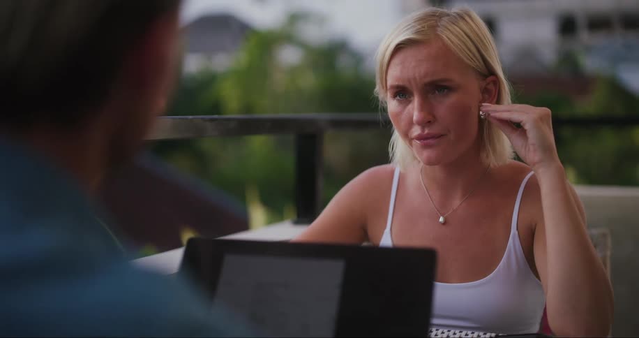 Man and woman sitting at a table with a laptop talking