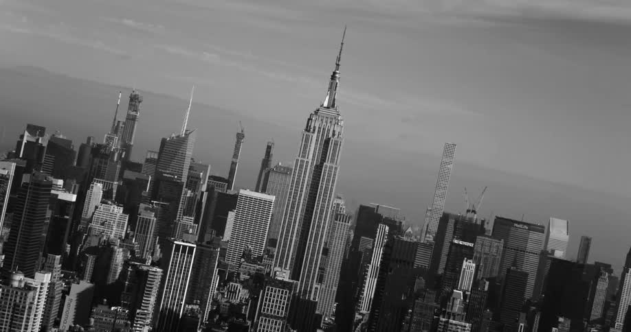 The empire state building in the center in black and white tones and below there are several other large buildings