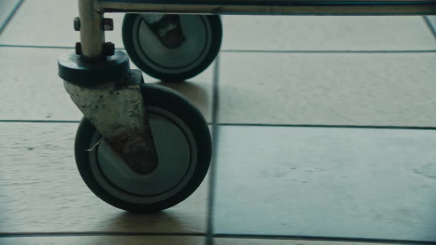 A person pushes a cart across a tiled floor
