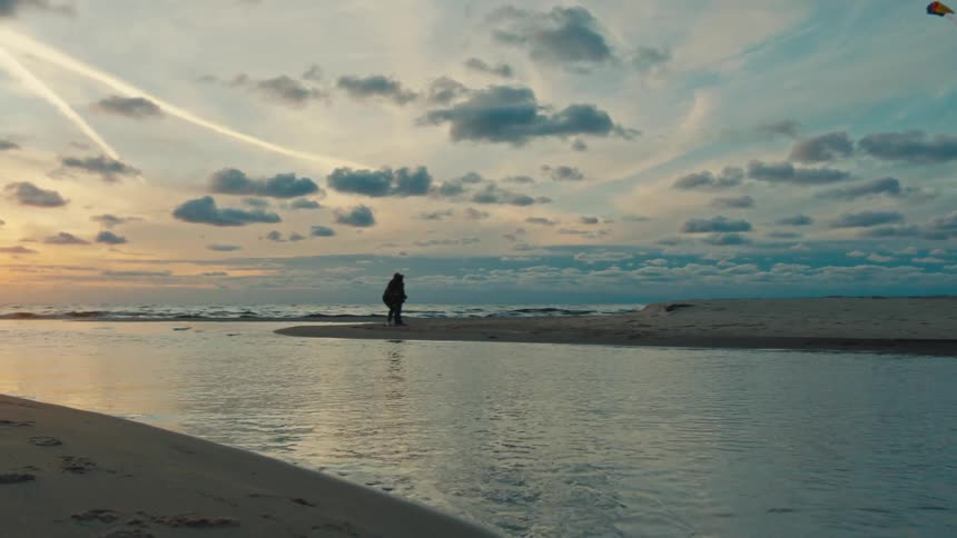 A body of water that meets the sea on a wave beach there is a person standing