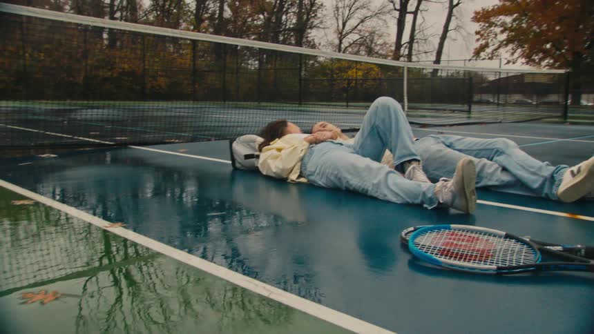 Man and woman lie on wet tennis court during fall