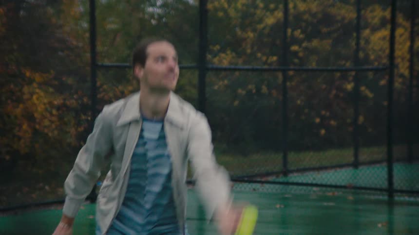 Male serving a tennis ball in an outdoor tennis court