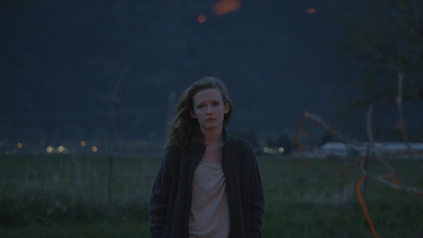 Sparks fly in the air around a teenage girl standing in an open area