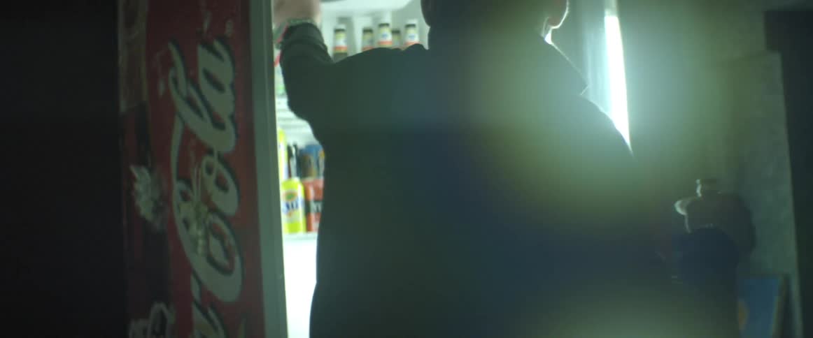 A man opens a retail refrigerator to grab a beverage