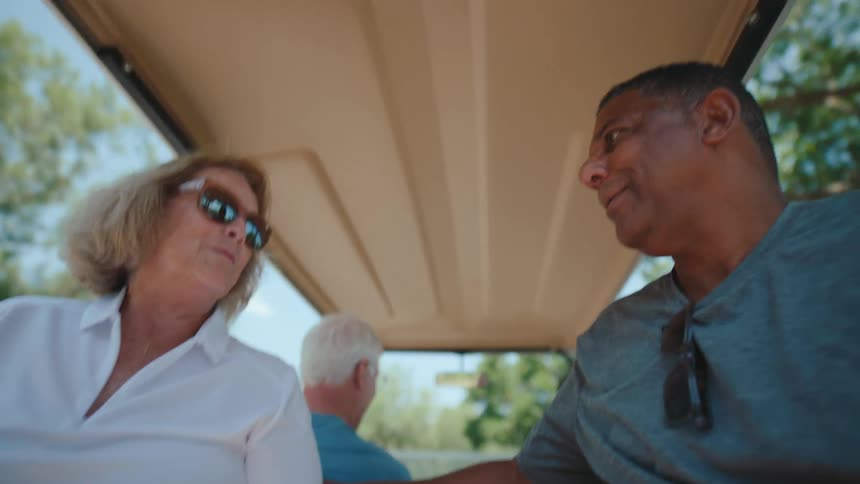 People talk while riding on a golf cart