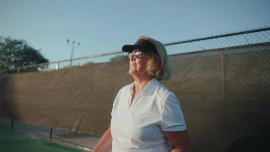 A woman hits the pickleball on the court