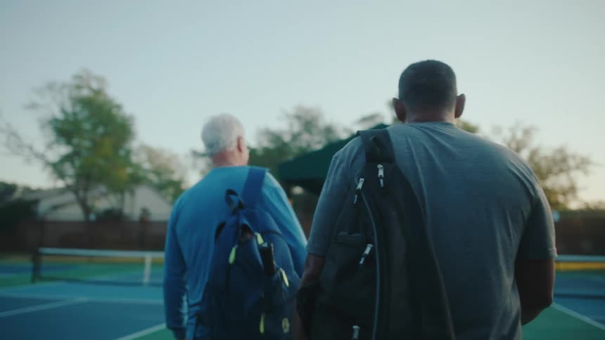 A group of people walk onto the tennis court