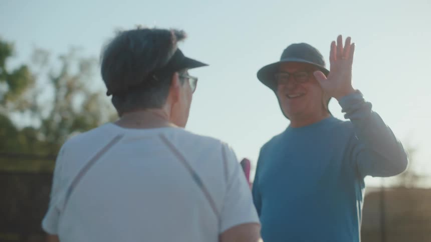 Teammates high five during a pickleball game