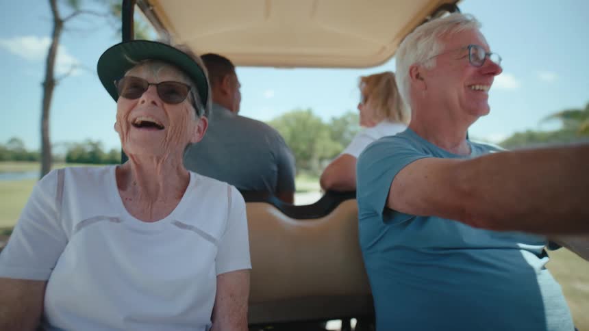 Four elderly people in a moving golf cart