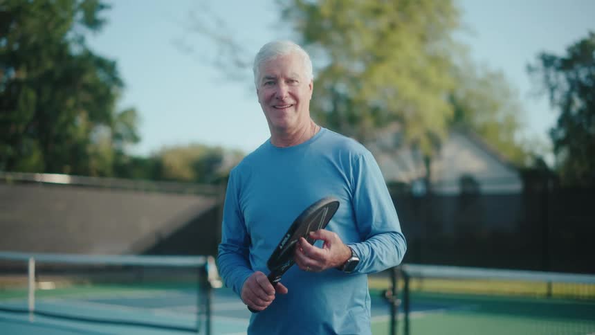 A man lifts his pickleball paddle on the court