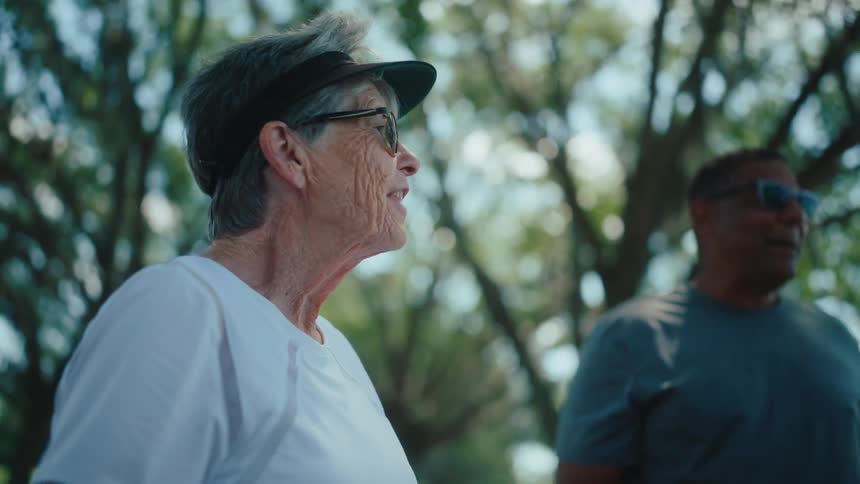 An elderly woman chatting with friends in a wooded area