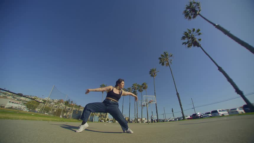 Woman in jeans dancing with palm trees around her
