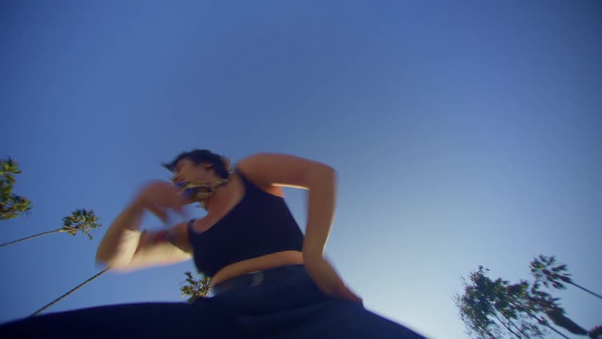 A woman breaks out the dance moves outdoors near numerous palm trees