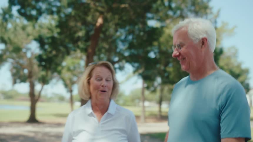 Elderly man and woman happily talking while walking outdoors