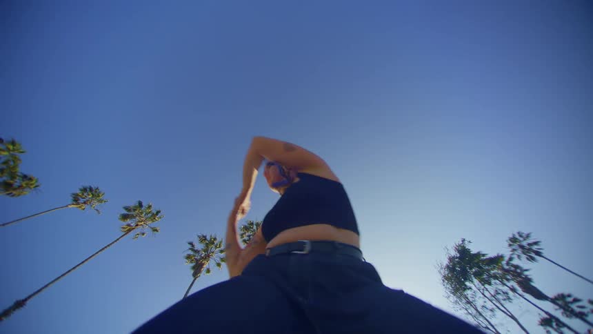 A woman dances under the palm trees