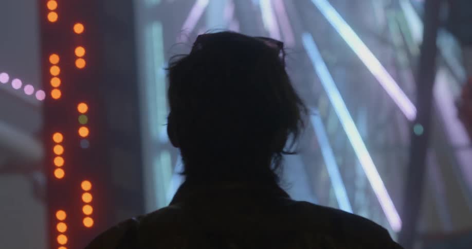 Man watching ferris wheel at night