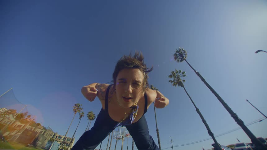 Woman in jeans dancing in a natural environment with palm trees around her