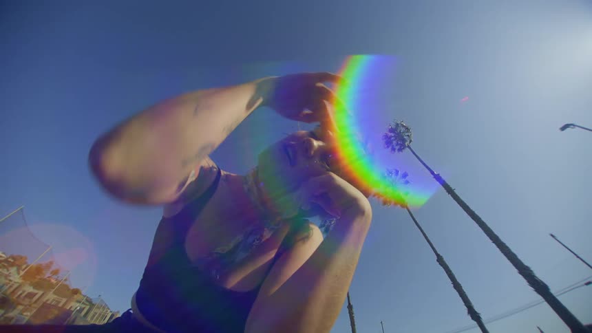 A woman with tattoos dances outdoors in the midday sun