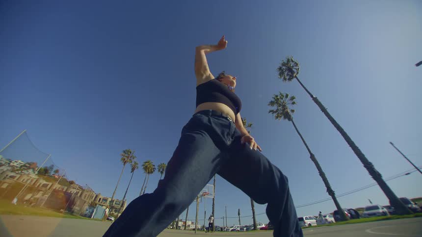 Woman dancing in a park on a cloudless blue sky day