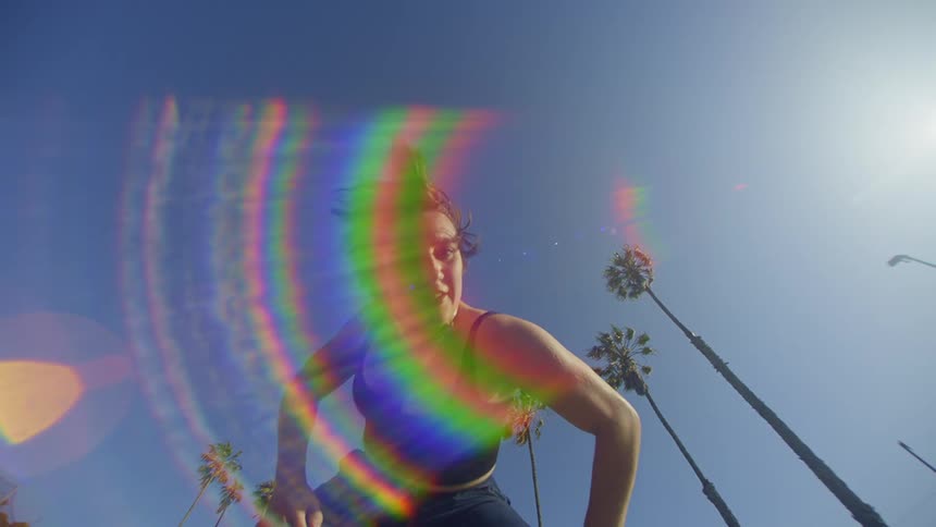 A female dances outdoors under a midday sun