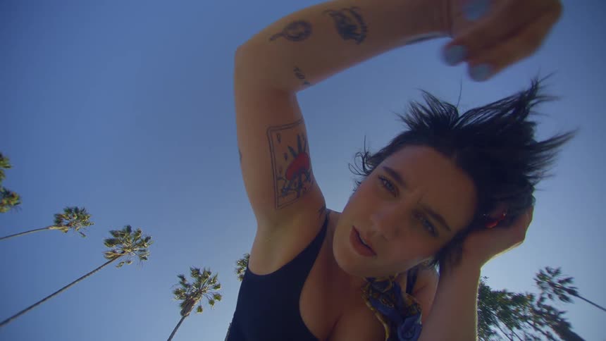 A woman making gestures with her arms in contrast to the blue sky in the background