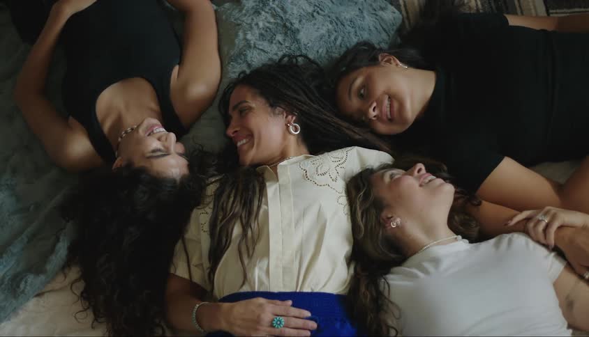 Portrait of a mother lying down with four smiling women of different ages beside her