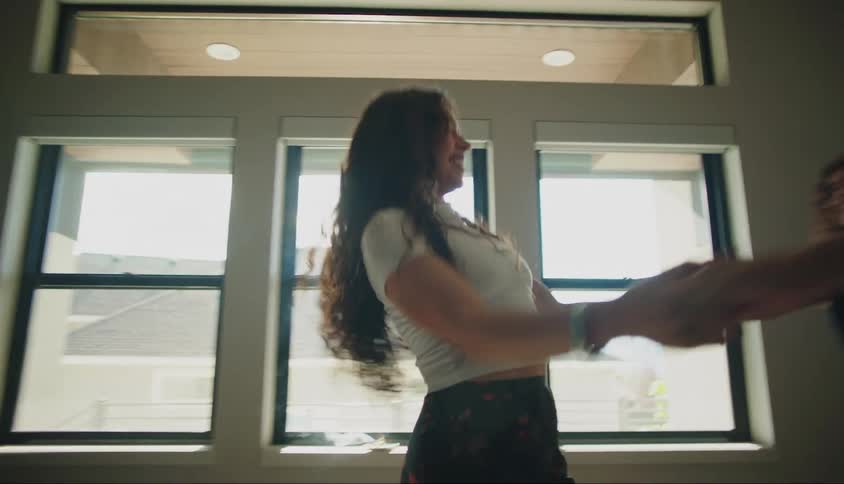 Three teenage girls do a circular dance in a living room