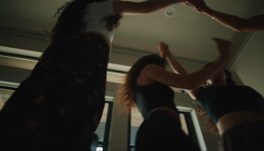Four teenage girls dance wildly in a house